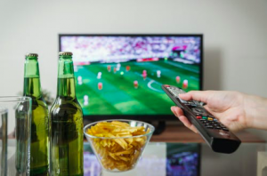 person watching a match on tv and placing online bets